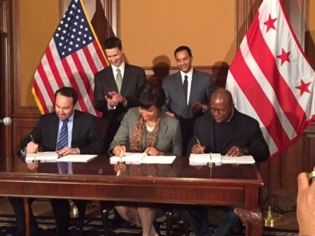 Mayor Bowser signs the Res. 13/Hill East LDA with Chris Donatelli of Donatelli Development (to her left) and Scottie Irving of Blue Skye Construction (to her right) while Ward 6 Councilmember Charles Allen and Deputy Mayor Brian Kenner look on. 